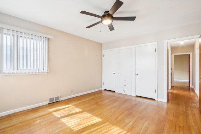 7700 3rd Ave, Kenosha, WI 53143 - unfurnished bedroom featuring light wood finished floors, baseboards, multiple closets, and ceiling fan