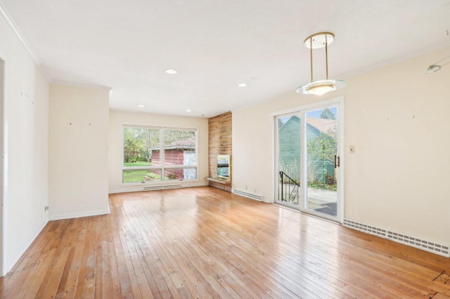 7700 3rd Ave, Kenosha, WI 53143 - unfurnished living room featuring light wood finished floors, baseboards, baseboard heating, a baseboard radiator, and crown molding