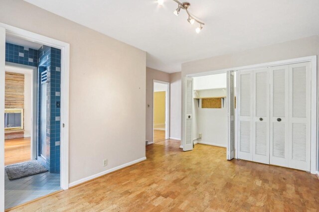 7700 3rd Ave, Kenosha, WI 53143 - unfurnished bedroom with baseboards, light wood-style floors, and two closets