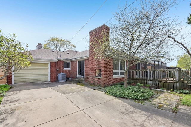 7700 3rd Ave, Kenosha, WI 53143 - rear view of house featuring a garage, brick siding, driveway, central AC, and a chimney
