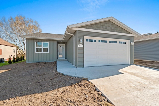 4551 Menasha Ave, Manitowoc, WI 54220 - ranch-style home with an attached garage, concrete driveway, board and batten siding, and a shingled roof