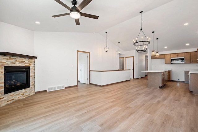 4551 Menasha Ave, Manitowoc, WI 54220 - unfurnished living room with a ceiling fan, a fireplace, a chandelier, light wood-type flooring, and lofted ceiling