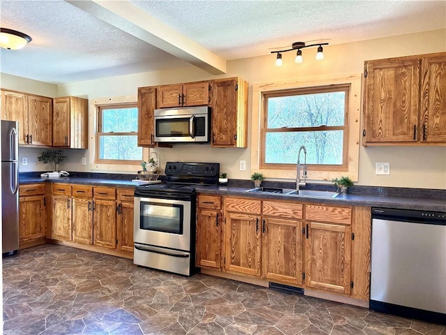 208 N 7th St, Cameron, WI 54822 - kitchen with stainless steel appliances, a sink, a textured ceiling, and brown cabinets
