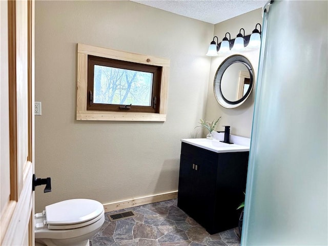 208 N 7th St, Cameron, WI 54822 - bathroom with baseboards, toilet, vanity, stone finish flooring, and a textured ceiling