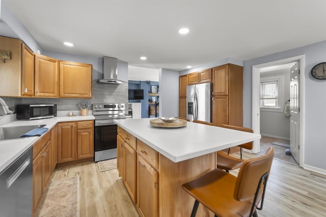 1301 Jackson St, Stoughton, WI 53589 - kitchen with stainless steel appliances, wall chimney exhaust hood, a sink, a kitchen bar, and light wood finished floors
