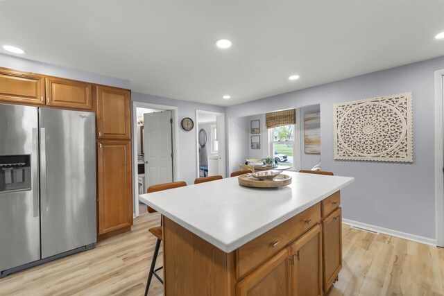 1301 Jackson St, Stoughton, WI 53589 - kitchen featuring stainless steel refrigerator with ice dispenser, light wood finished floors, a breakfast bar, a center island, and light countertops