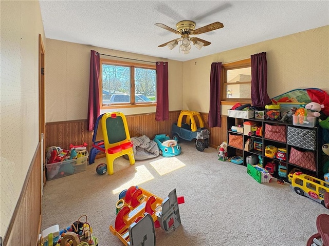 501 S 8th St, Luck, WI 54853 - recreation room with wainscoting, carpet flooring, ceiling fan, wood walls, and a textured ceiling