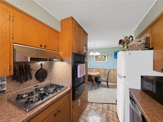 501 S 8th St, Luck, WI 54853 - kitchen featuring under cabinet range hood, stainless steel gas stovetop, black oven, a warming drawer, and a chandelier