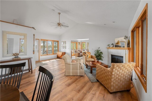 29825 Minerva Cir, Danbury, WI 54830 - living area with light wood-style floors, a ceiling fan, a tile fireplace, high vaulted ceiling, and baseboards