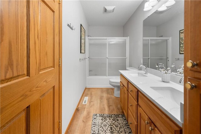 29825 Minerva Cir, Danbury, WI 54830 - full bathroom with wood finished floors, double vanity, toilet, bath / shower combo with glass door, and baseboards