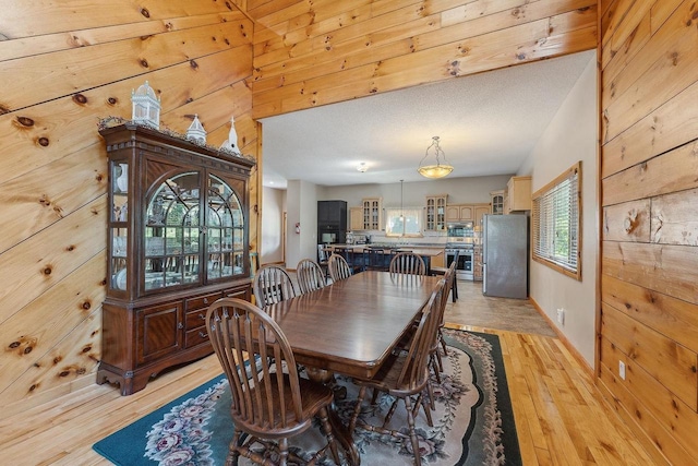 E9510 Oak Hill Rd, Wisconsin Dells, WI 53965 - dining room featuring wood walls, light wood-style floors, and baseboards