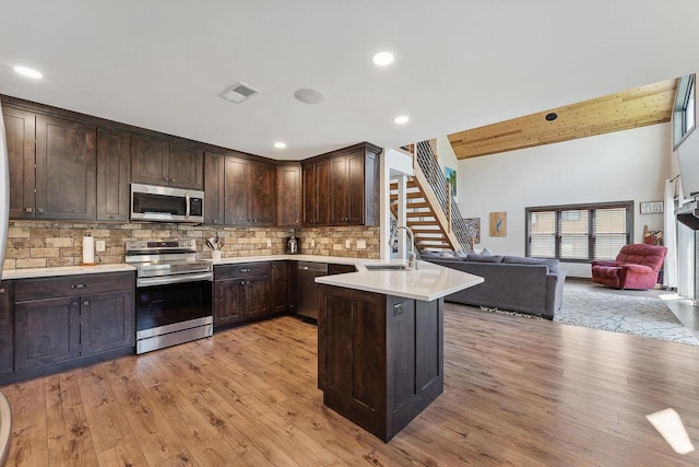 S952 W Redstone Dr, La Valle, WI 53941 - kitchen featuring appliances with stainless steel finishes, a sink, open floor plan, dark brown cabinetry, and light wood-style floors