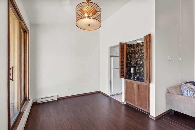 unfurnished living room with a baseboard radiator, dark wood finished floors, a high ceiling, and baseboards