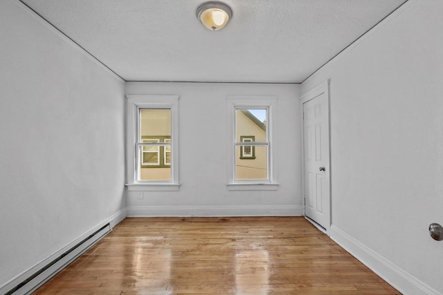 2535 N 48th St, Milwaukee, WI 53210 - spare room with a baseboard heating unit, light wood-style floors, baseboards, and a textured ceiling
