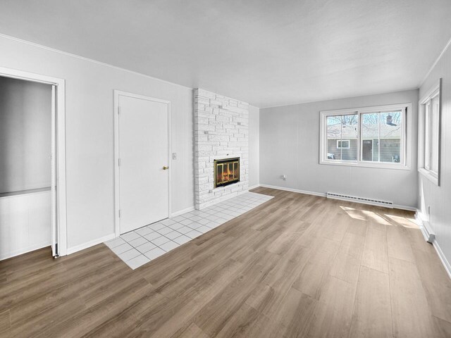 4538 Oakdale Dr, Racine, WI 53405 - unfurnished living room featuring baseboard heating, wood finished floors, a fireplace, and baseboards
