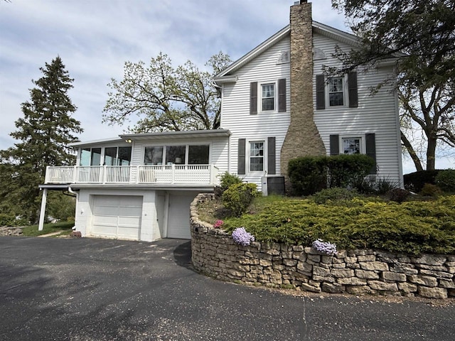 1263 N Parker Dr, Janesville, WI 53545 - view of front of house with a chimney, an attached garage, asphalt driveway, and a balcony