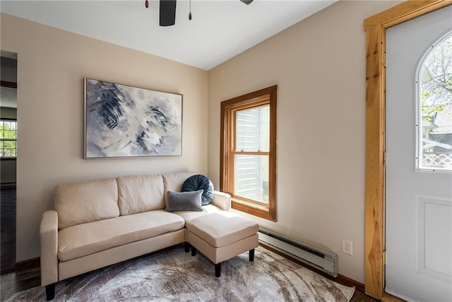 living area with a baseboard heating unit, a ceiling fan, and healthy amount of natural light