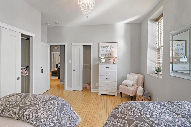 9302 39th Ave, Pleasant Prairie, WI 53158 - bedroom with light wood-type flooring, two closets, a chandelier, and baseboards