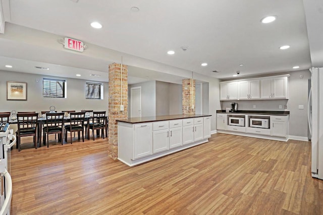 9302 39th Ave, Pleasant Prairie, WI 53158 - kitchen featuring white appliances, dark countertops, decorative columns, light wood-style flooring, and white cabinets