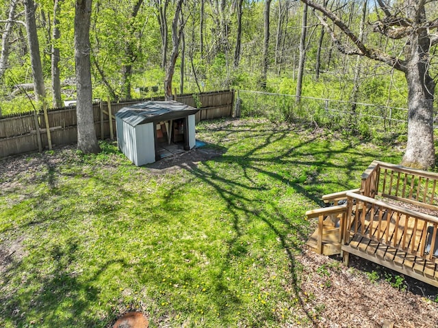 view of yard featuring a shed, an outbuilding, a wooded view, and a wooden deck