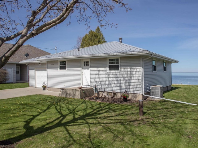 N9569 Bay Shore Ln, Luxemburg, WI 54217 - view of front of property with an attached garage, concrete driveway, central AC, a front lawn, and a water view