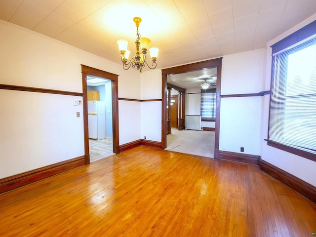 unfurnished dining area featuring a chandelier, hardwood / wood-style floors, healthy amount of natural light, a ceiling fan, and crown molding