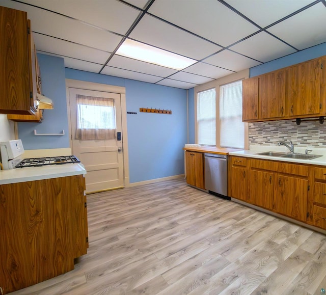 kitchen with a sink, dishwasher, white gas stove, brown cabinetry, and light countertops