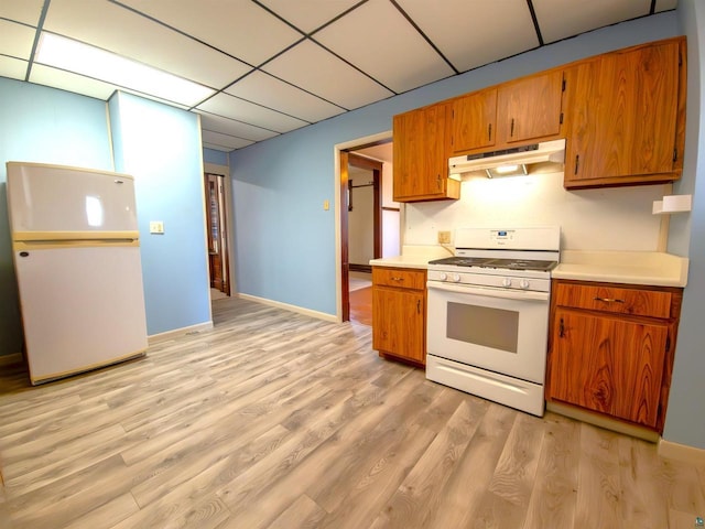 kitchen with white appliances, under cabinet range hood, brown cabinetry, light wood-style floors, and light countertops
