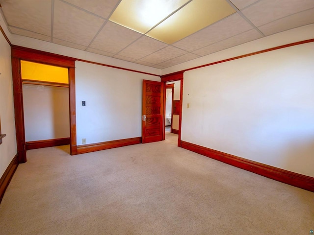 carpeted spare room featuring baseboards and a drop ceiling