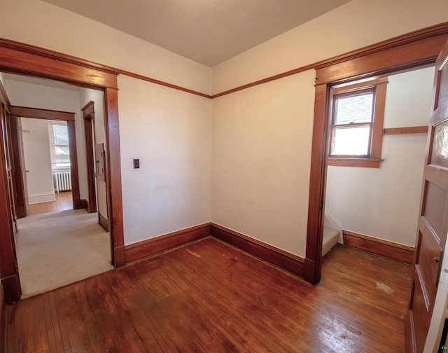 spare room with radiator, hardwood / wood-style floors, baseboards, and healthy amount of natural light