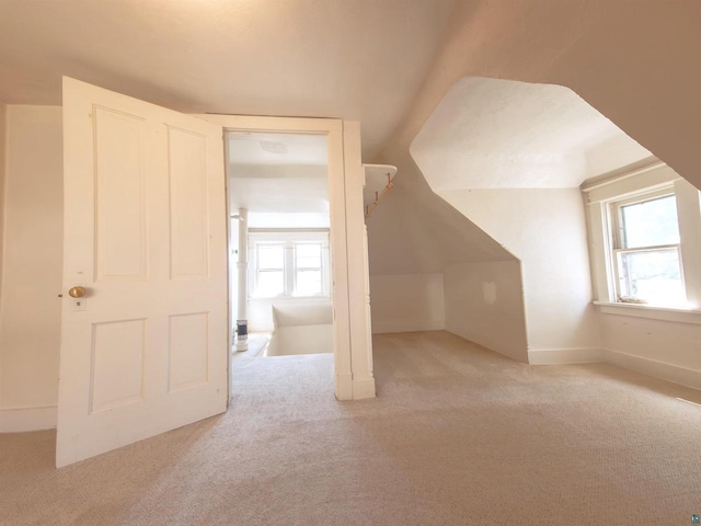 bonus room featuring carpet flooring, healthy amount of natural light, lofted ceiling, and baseboards