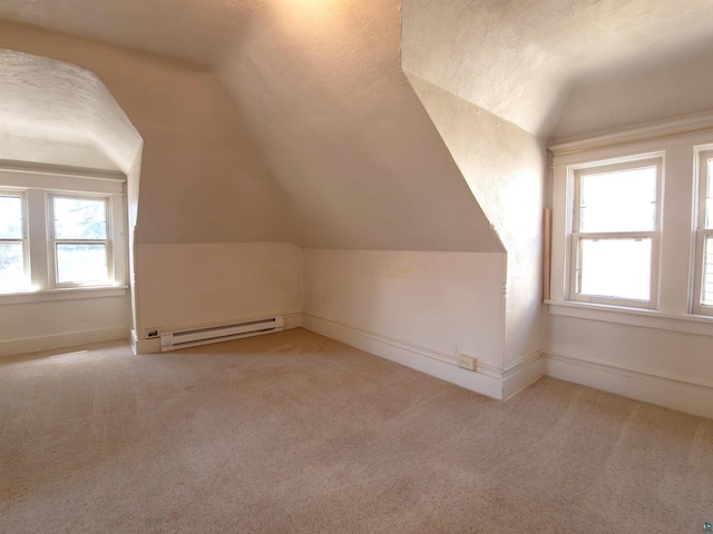 additional living space with a baseboard heating unit, vaulted ceiling, carpet floors, and baseboards