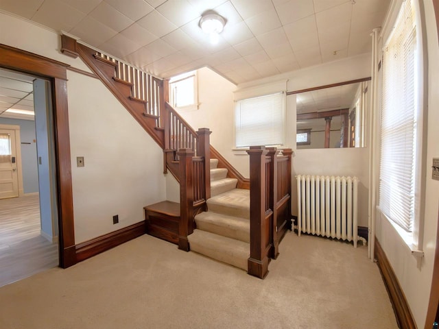 stairs with radiator, carpet floors, and baseboards