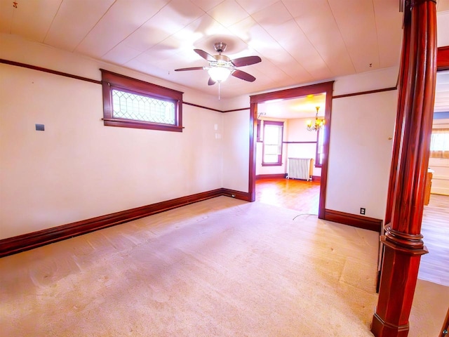 carpeted empty room with radiator heating unit, ceiling fan, baseboards, and ornate columns