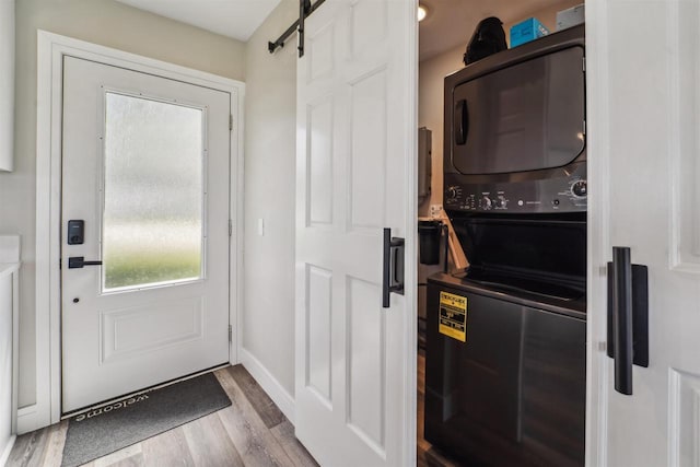N8432 Minawa Beach Rd, Fond Du Lac, WI 54937 - clothes washing area with estacked washer and dryer, wood finished floors, a barn door, and baseboards