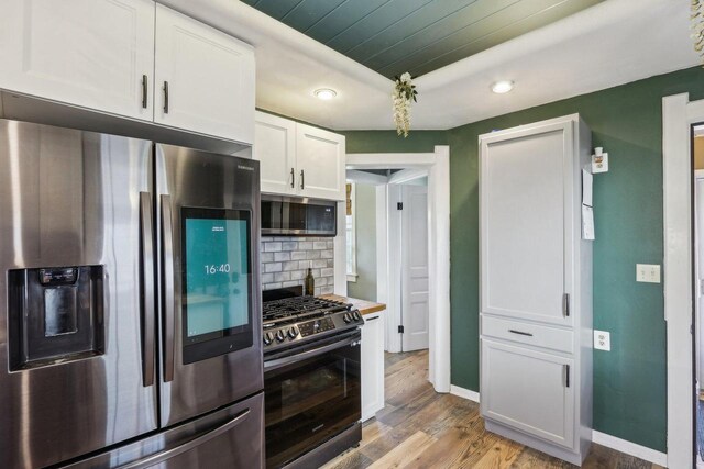 114 E Washington St, West Bend, WI 53095 - kitchen featuring appliances with stainless steel finishes, white cabinets, light wood finished floors, wooden ceiling, and tasteful backsplash