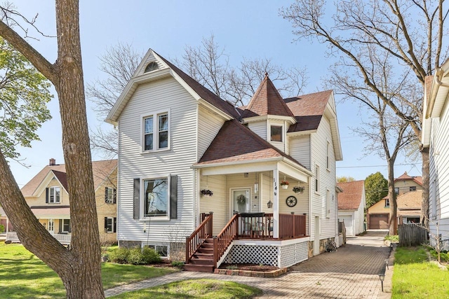 114 E Washington St, West Bend, WI 53095 - victorian house featuring a front yard, covered porch, a shingled roof, and a detached garage