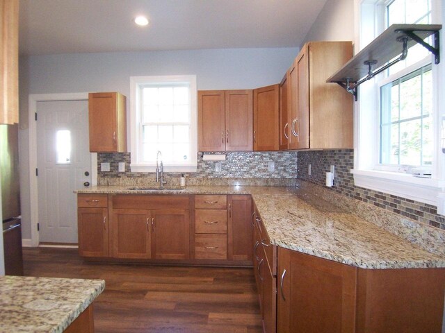 929 Park Ave, Beloit, WI 53511 - kitchen featuring a sink, brown cabinets, dark wood finished floors, decorative backsplash, and light stone counters