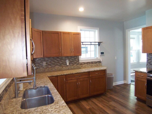 929 Park Ave, Beloit, WI 53511 - kitchen featuring a sink, decorative backsplash, dark wood-style floors, brown cabinetry, and light stone countertops