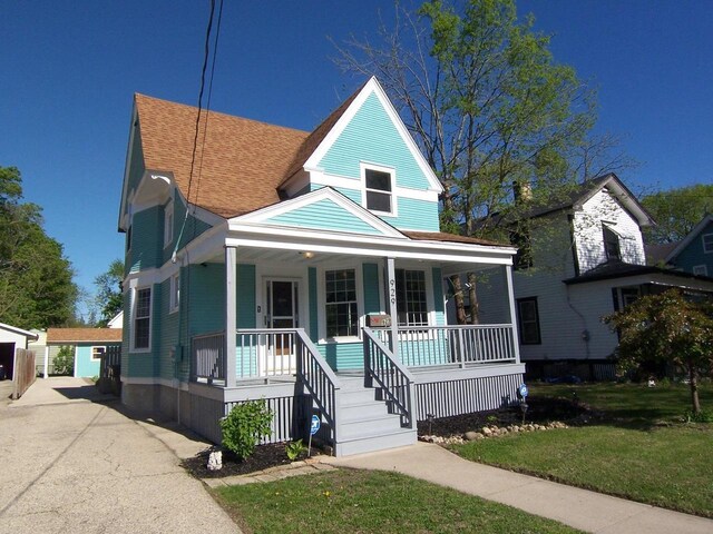 929 Park Ave, Beloit, WI 53511 - view of front of property with covered porch, a front yard, an outbuilding, and a shingled roof