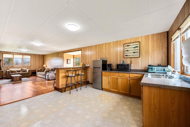 2965 S Stevenson Pier Rd, Sturgeon Bay, WI 54204 - kitchen featuring black microwave, freestanding refrigerator, brown cabinetry, light flooring, and a kitchen bar