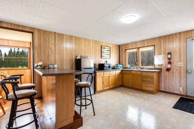 2965 S Stevenson Pier Rd, Sturgeon Bay, WI 54204 - kitchen featuring stainless steel appliances, a drop ceiling, healthy amount of natural light, a kitchen breakfast bar, and wood walls
