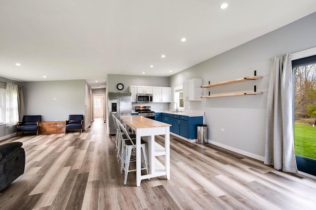 2965 S Stevenson Pier Rd, Sturgeon Bay, WI 54204 - kitchen featuring appliances with stainless steel finishes, blue cabinets, recessed lighting, light wood-type flooring, and light countertops