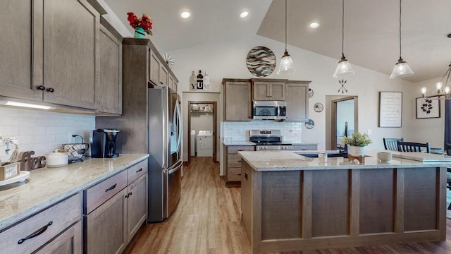2239 E Honeygold Ct, Appleton, WI 54913 - kitchen with appliances with stainless steel finishes, washer / dryer, vaulted ceiling, tasteful backsplash, and light wood-type flooring