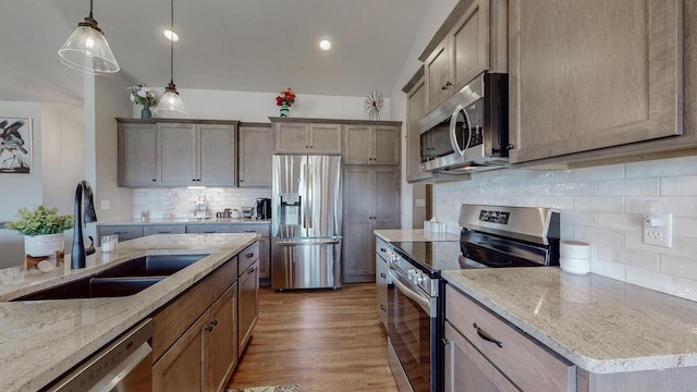 2239 E Honeygold Ct, Appleton, WI 54913 - kitchen featuring appliances with stainless steel finishes, a sink, decorative backsplash, pendant lighting, and light stone counters