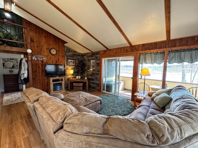 living room with wooden walls, wood finished floors, beam ceiling, and high vaulted ceiling