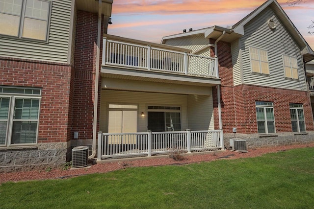670 E Lake Ave Unit 202, Wisconsin Dells, WI 53940 - back of property at dusk with a balcony, brick siding, central AC unit, and a lawn
