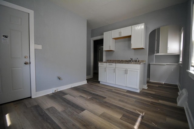 2625 N 50th St, Milwaukee, WI 53210 - kitchen featuring white cabinets, arched walkways, dark wood finished floors, and baseboards