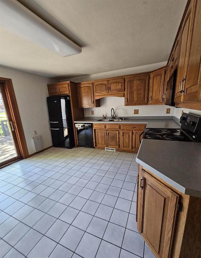 1247 Goss Ave, Menasha, WI 54952 - kitchen with black appliances, a sink, light tile patterned floors, brown cabinetry, and a textured ceiling