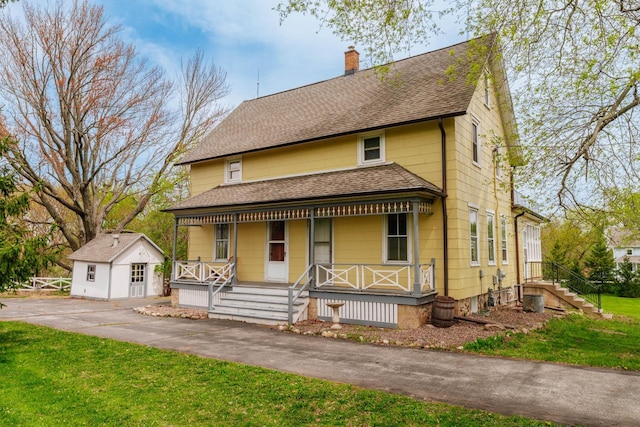 12220 W Highland Rd, Mequon, WI 53097 - view of front facade with roof with shingles, a chimney, covered porch, an outdoor structure, and a front yard